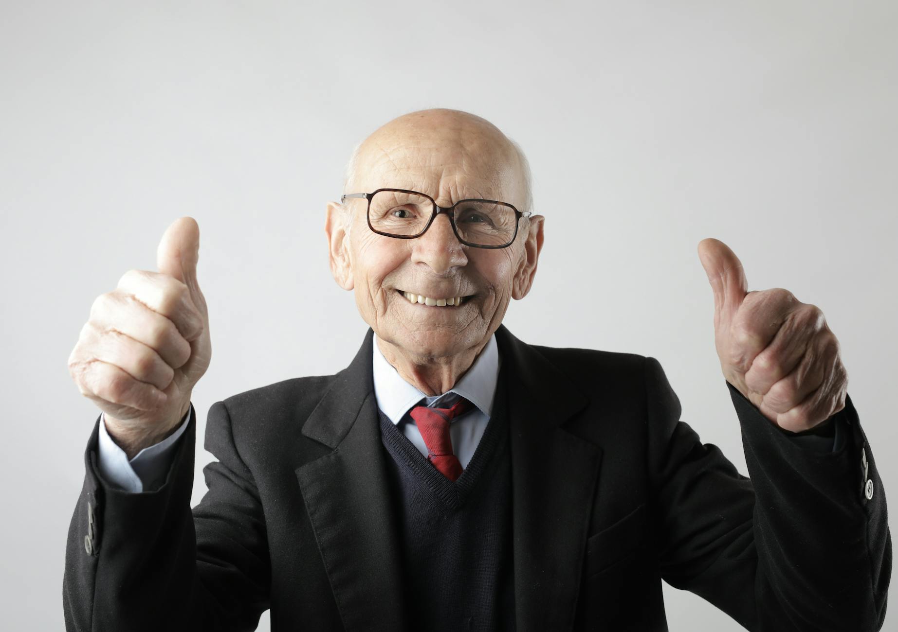 Positiver älterer Mann In Der Brille, Die Daumen Oben Zeigt Und Kamera Betrachtet